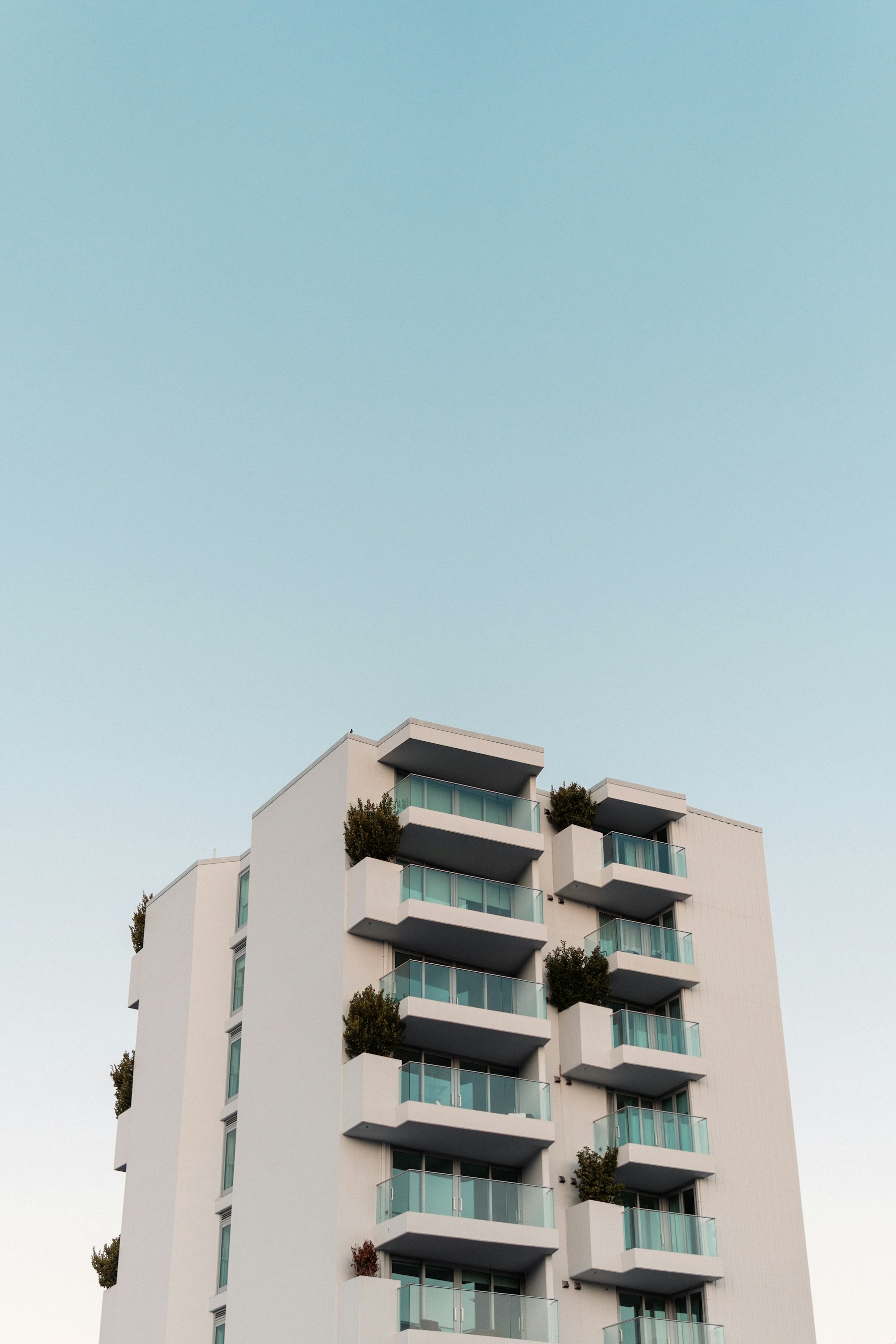 Edificio residencial con balcones y vegetación, contra un cielo despejado.
