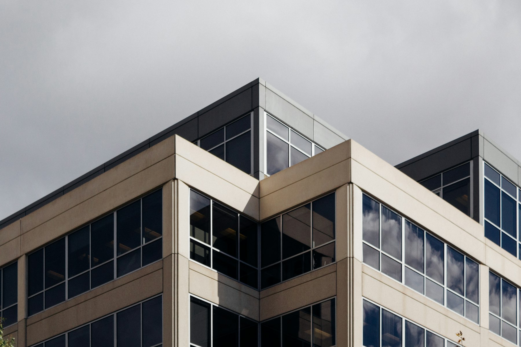 Esquina superior de un edificio de oficinas de líneas rectas y ventanales continuos.
